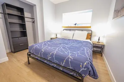 a bedroom with a bed with a blue comforter at Storm Bay, Modern 1 Bed Suite and Chefs Kitchen in Ucluelet