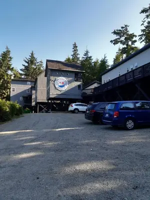 a parking lot with cars parked in front of a building at Fern Gully, Coastal Bohemian Loft at Beach in Ucluelet