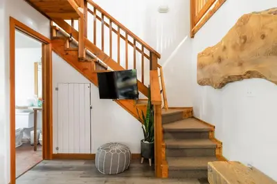 a living room with a staircase with a flat screen tv at Fern Gully, Coastal Bohemian Loft at Beach in Ucluelet