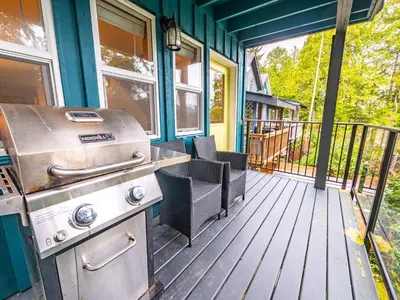 a grill on the front porch of a house at Kingfisher, Waterfront Cabin with Inlet with Mountain Views in Ucluelet