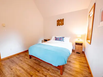 a small bedroom with a bed and a wooden floor at Kingfisher, Waterfront Cabin with Inlet with Mountain Views in Ucluelet