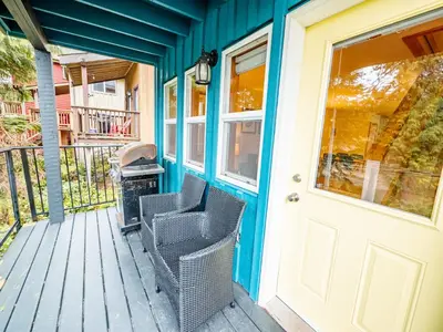 a front porch with two chairs and a grill at Kingfisher, Waterfront Cabin with Inlet with Mountain Views in Ucluelet