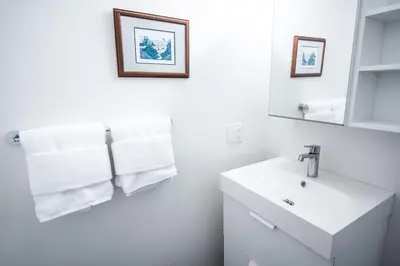 a white bathroom with a sink and a mirror at Kingfisher, Newly Renovated Suite on Ocean Inlet in Ucluelet