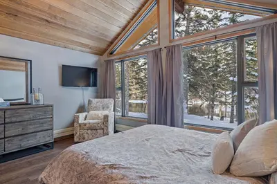 a bedroom with a bed and a tv and windows at Canmore Cabin by Canadian Rockies Vacation Rentals in Canmore