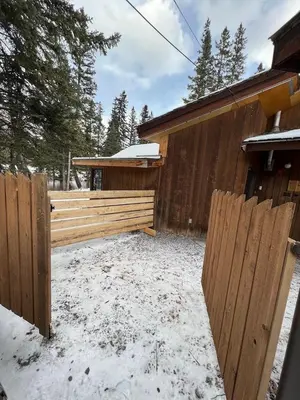 a wooden fence in the snow next to a house at Canmore Cabin by Canadian Rockies Vacation Rentals in Canmore