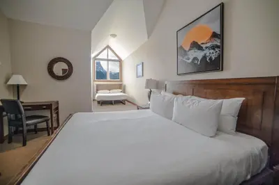 a bedroom with a bed and a desk and a window at Spacious Penthouse Suite-King Beds-Pool & Hot Tub in Canmore