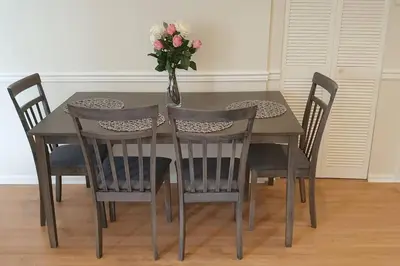 a dining room table with chairs and a vase with flowers at Happy, Cozy, Loving Guest Space in West Vancouver in West Vancouver