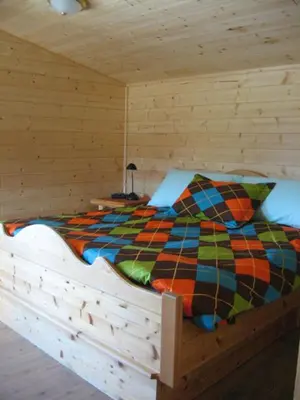 a bed in a wooden cabin with a colorful comforter at Tschurtschenthaler Rentals in Golden