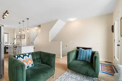a living room with two green chairs and a kitchen at Casa de Luna by Canadian Rockies Vacation Rentals in Canmore
