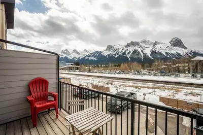 a red chair sitting on a balcony with snow covered mountains at Casa de Luna by Canadian Rockies Vacation Rentals in Canmore