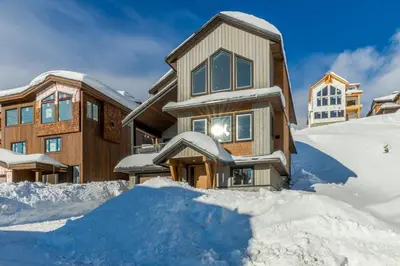 a house with a pile of snow in front of it at The White Pearl - Amazing Luxury Chalet with Mountain Views in Big White