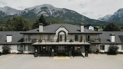 a large building with mountains in the background at Northwinds Hotel Canmore in Canmore