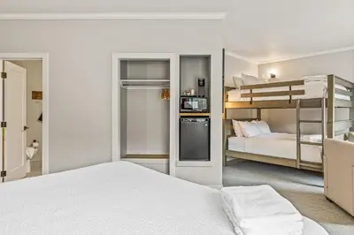 a bedroom with two bunk beds and a kitchen at Northwinds Hotel Canmore in Canmore