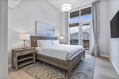 a bedroom with a bed and a large window at BRAND NEW - Gorgeous Spring Creek Penthouse in Canmore