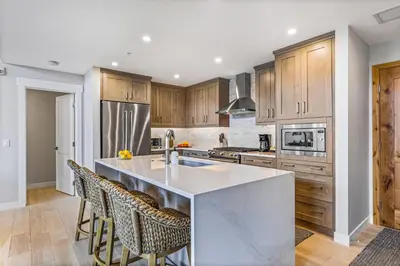 a kitchen with a large island with bar stools at BRAND NEW - Gorgeous Spring Creek Penthouse in Canmore