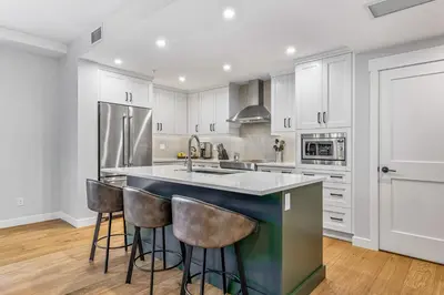 a kitchen with white cabinets and a kitchen island with bar stools at Spring Creek Vacations in Canmore
