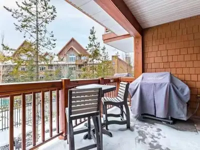 a patio with a table and chairs on a balcony at Sunny Tranquil Woods Turret in Falcon Crest Lodge in Canmore