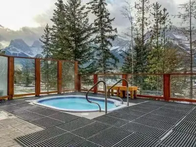 a hot tub on a deck with a view of mountains at Sunny Tranquil Woods Turret in Falcon Crest Lodge in Canmore