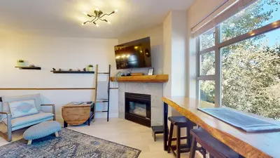 a living room with a fireplace and a table at 1BR plus Den in Marketplace Lodge, Village Location, Mountain Views, Complex Hot Tub in Whistler