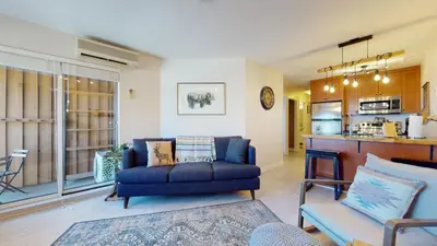 a living room with a blue couch and a kitchen at 1BR plus Den in Marketplace Lodge, Village Location, Mountain Views, Complex Hot Tub in Whistler
