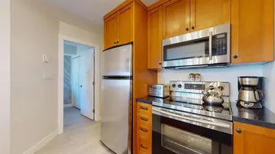 a kitchen with stainless steel appliances and wooden cabinets at 1BR plus Den in Marketplace Lodge, Village Location, Mountain Views, Complex Hot Tub in Whistler