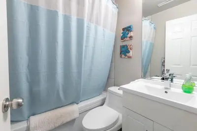 a bathroom with a white toilet and a blue shower curtain at Suite Sunrise in Vancouver