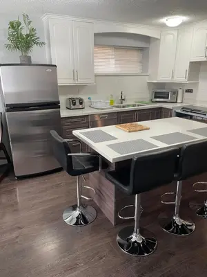 a kitchen with a refrigerator and a table with bar stools at Suite Sunrise in Vancouver
