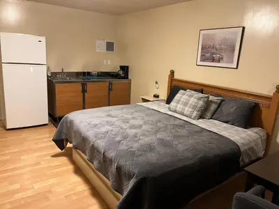 a bedroom with a bed and a kitchen with a refrigerator at Kings Court Motel in Cold Lake