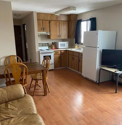 a kitchen with a table and a white refrigerator at Kings Court Motel in Cold Lake