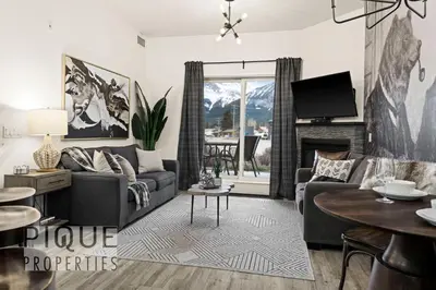 a living room with a couch and a tv at Mountain Haven Retreat, Pool & Hot Tub, UG Parking, Fitness Centre, WiFi! in Canmore