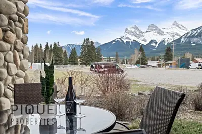 a table with two bottles of wine on it with mountains at Mountain Haven Retreat, Pool & Hot Tub, UG Parking, Fitness Centre, WiFi! in Canmore