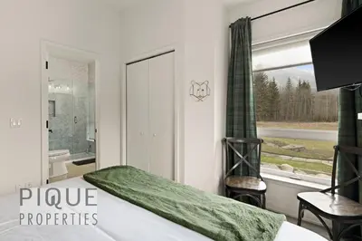 a bedroom with a bed and a bathroom with a window at Mountain Haven Retreat, Pool & Hot Tub, UG Parking, Fitness Centre, WiFi! in Canmore