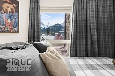 a bedroom with a couch and a window with mountains at Mountain Haven Retreat, Pool & Hot Tub, UG Parking, Fitness Centre, WiFi! in Canmore