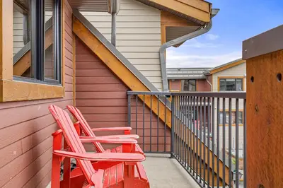 two red chairs sitting on the balcony of a house at Alluring Mountain View Condo - Right In The Heart Of Downtown - managed by Little Sister Getaways in Canmore
