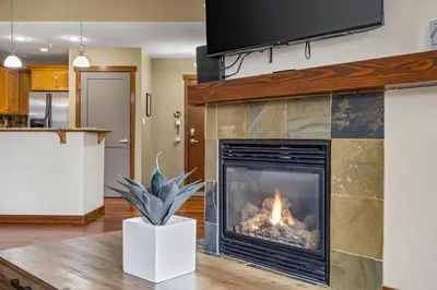 a fireplace in a living room with a fire at Alluring Mountain View Condo - Right In The Heart Of Downtown - managed by Little Sister Getaways in Canmore