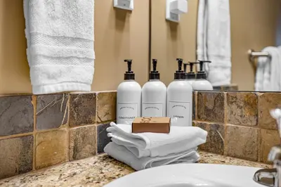 a bathroom counter with three bottles of soap and towels at Alluring Mountain View Condo - Right In The Heart Of Downtown - managed by Little Sister Getaways in Canmore