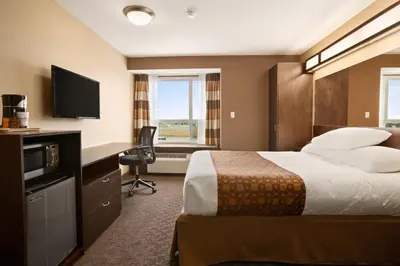 a hotel room with a bed and a flat screen tv at Microtel Inn & Suites by Wyndham Blackfalds in Blackfalds