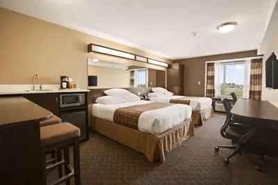 a hotel room with two beds and a desk and a sink at Microtel Inn & Suites by Wyndham Blackfalds in Blackfalds