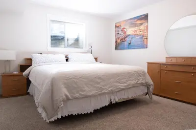 a bedroom with a bed with a mirror and a dresser at Modern yet comfy 3 bed suite in Surrey in Surrey