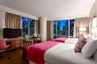 a hotel room with two beds and a desk with a television at Auberge Vancouver Hotel in Vancouver