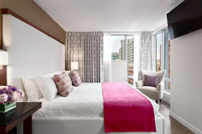 a bedroom with a bed and a chair and a window at Auberge Vancouver Hotel in Vancouver