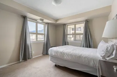 a bedroom with a bed and two windows at Lookout Pointe, Lakeview, Pool, Hot Tub, Gym in Invermere