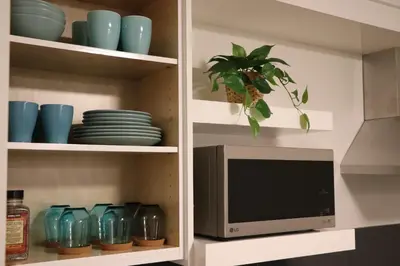 a tv in a kitchen with blue dishes and a plant at Harrison Grand Motel in Harrison Hot Springs