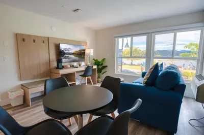 a living room with a blue couch and a table at Harrison Grand Motel in Harrison Hot Springs