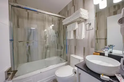 a bathroom with a toilet and a sink and a shower at Harrison Grand Motel in Harrison Hot Springs