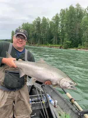 a man holding a large fish in a boat at LuxQuarters Kitimat River Suite in Kitimat