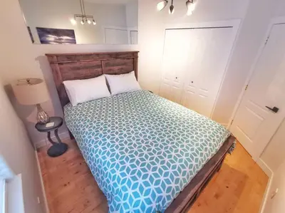 a bedroom with a bed with a blue comforter at LuxQuarters Kitimat River Suite in Kitimat