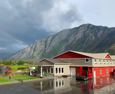 a red and white building with a mountain in the background at Orchard View Motel in Keremeos