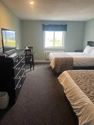a hotel room with two beds and a dresser at Orchard View Motel in Keremeos
