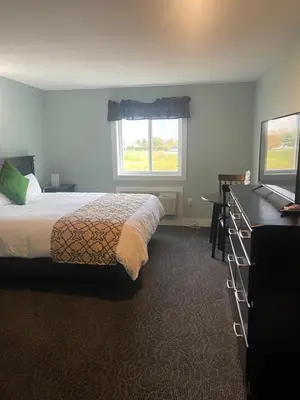 a bedroom with a bed and a television and a window at Orchard View Motel in Keremeos